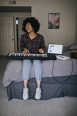 Woman playing keyboard on bed